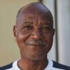 A joyful portrait of an elderly African man with a mustache, enjoying the sunlight.