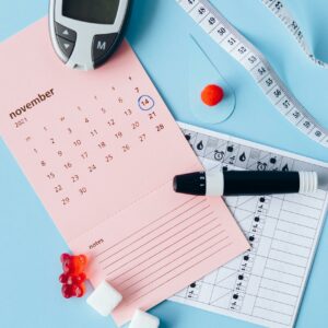 Flat lay of diabetes awareness tools on a blue backdrop with calendar.
