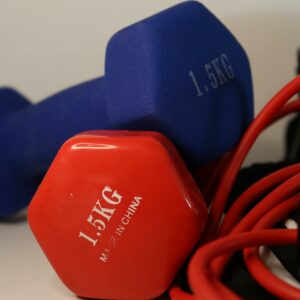 A vibrant close-up of 1.5kg dumbbells and red resistance bands on a white background.